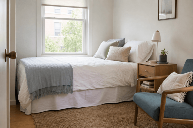 A small bedroom with a clear floor and simple bedside table
